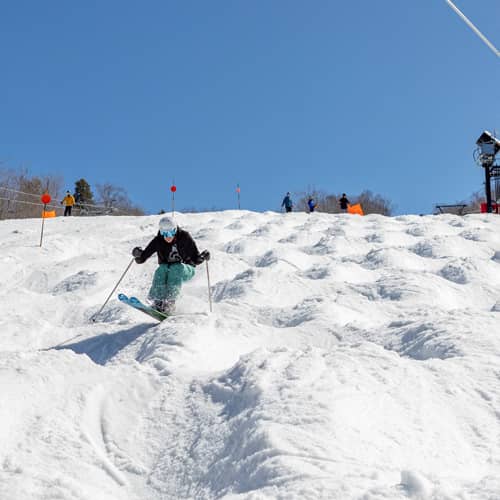 Skier on moguls in the spring with blue sky