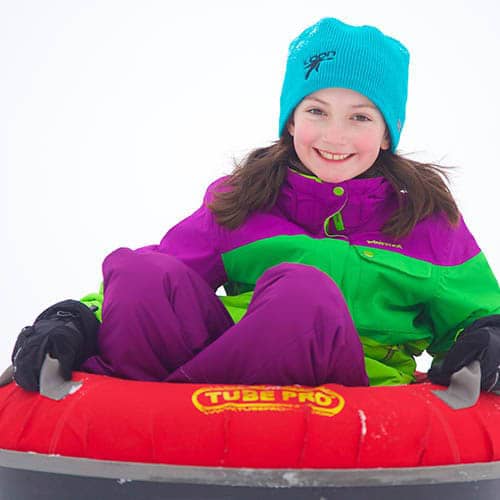 young girl sliding in snow tubes